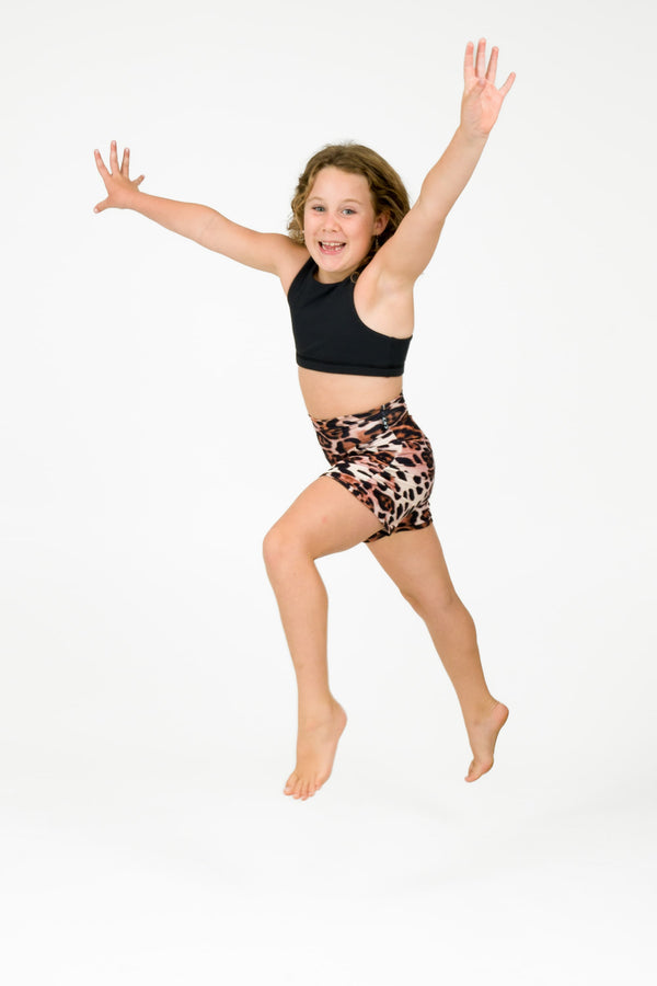 Young girl wearing activewear shorts in a leopard primal print for sports and gymnastics from exotica athletica