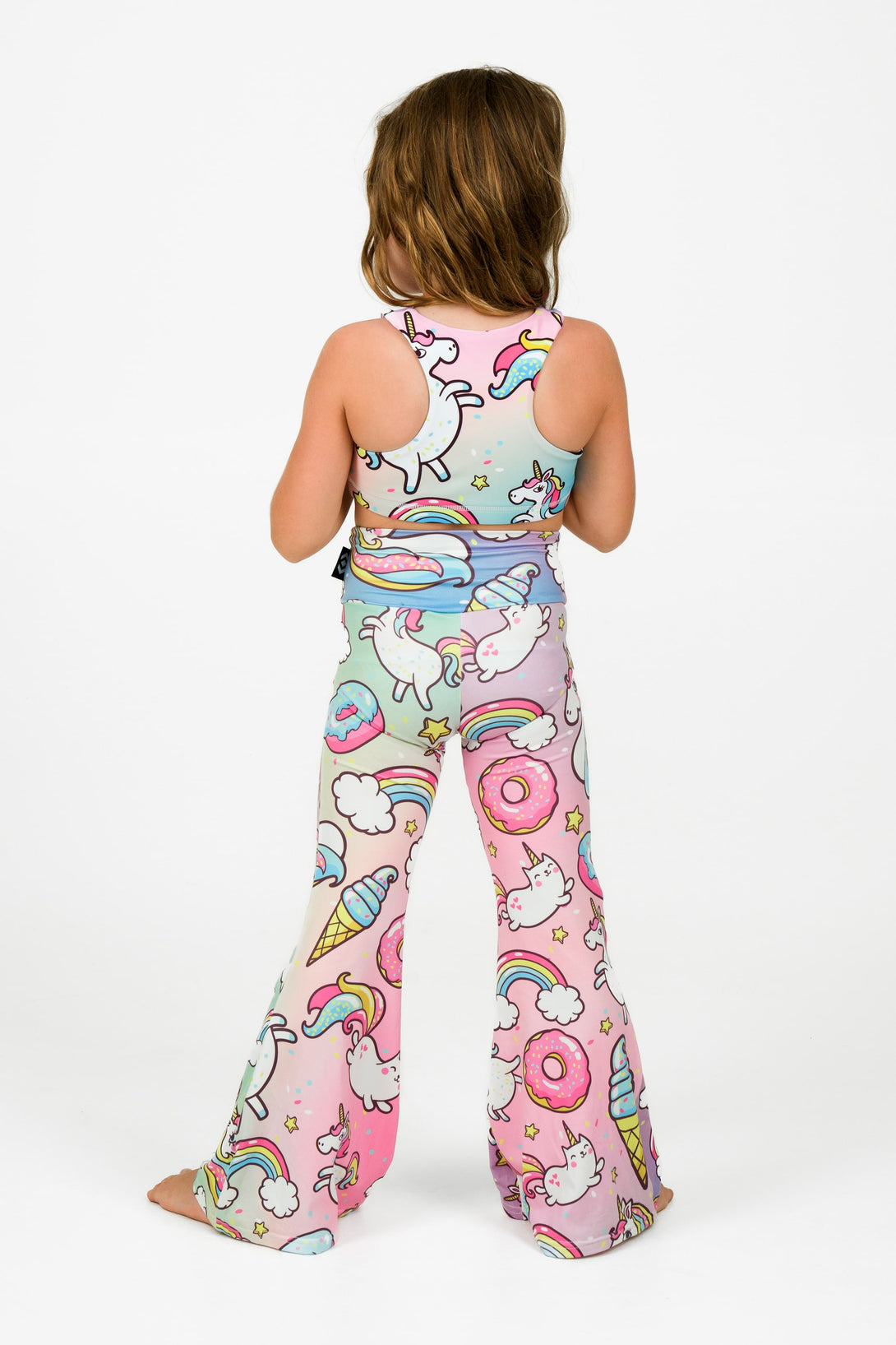 Young girl wearing activewear and loungewear from exotica athletica in a unicorn print bell leg pants